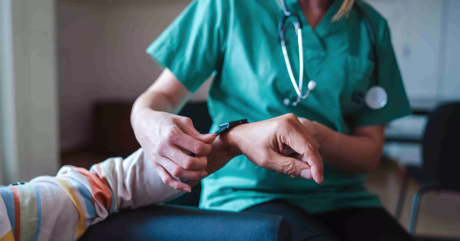 Medical professional wearing scrubs and stethoscope takes care of patient
